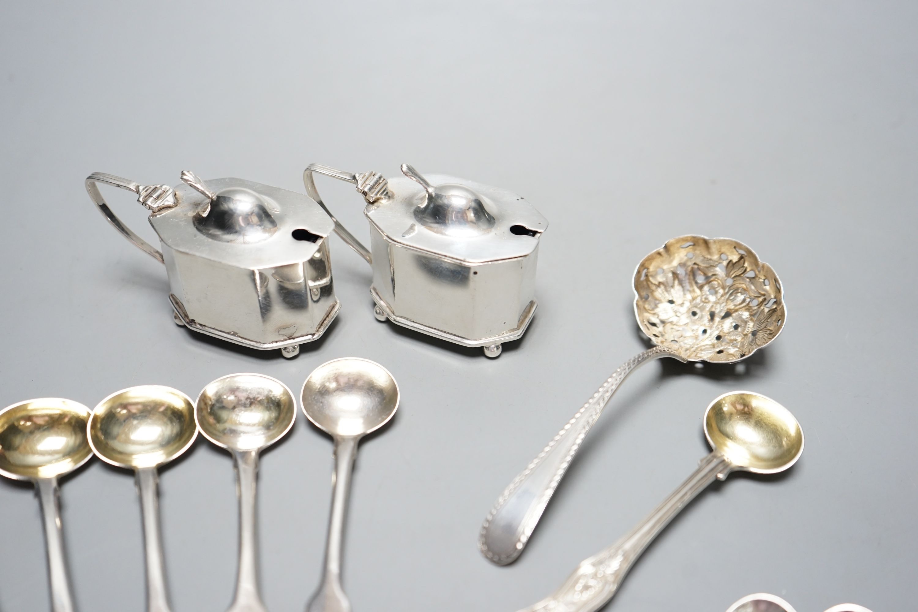 Seven assorted Georgian silver mustard ladles , a strainer, a pair of silver mustard pots and four spoons.